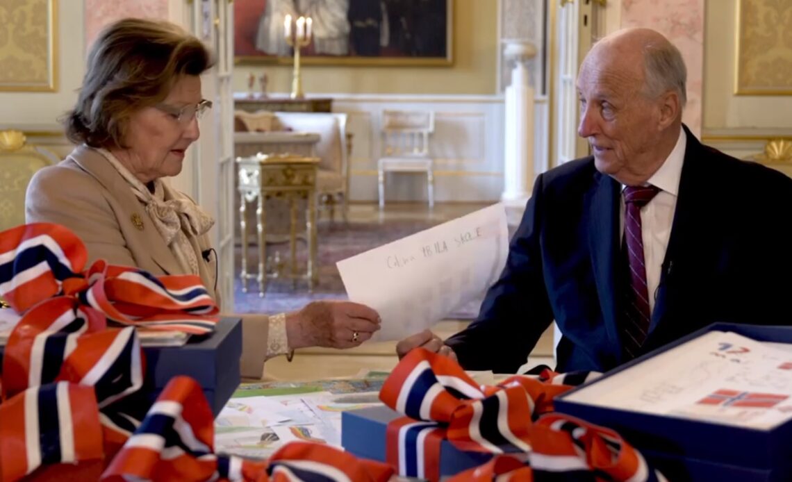 King Harald and Queen Sonja look at drawings sent to them by children to mark National Day 2021