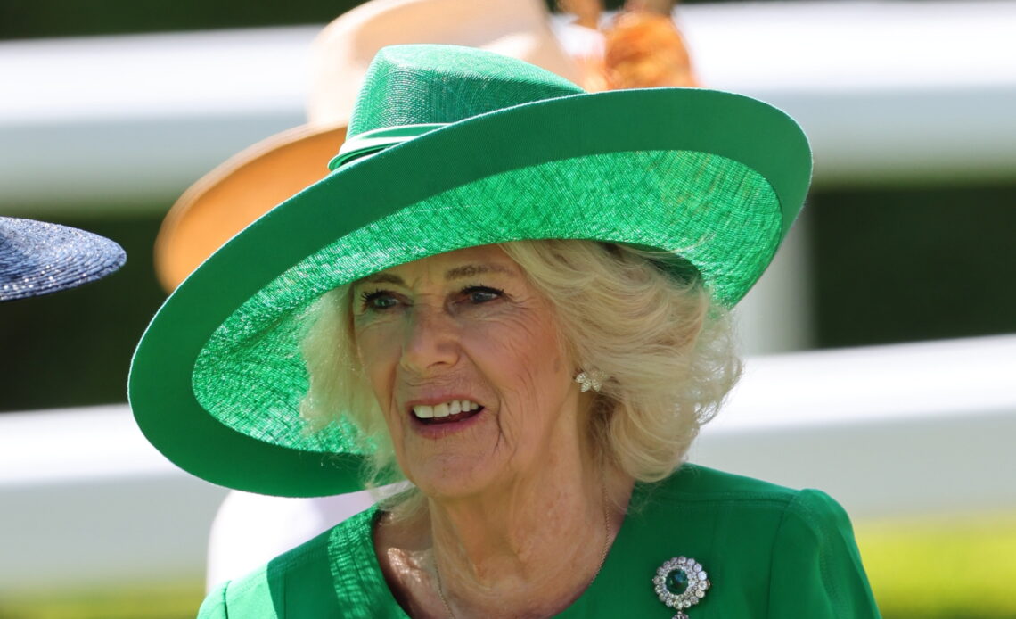 Queen Camilla arrives on day two of Royal Ascot. The Queen wears a deep green coat with matching, wide brimmed hat. Her jewellery includes an emerald and diamond brooch that has a scandalous royal history.