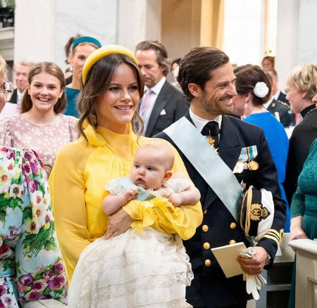 Princess Sofia carries her daughter, Princess Ines, through the royal chapel at the baby's christening with future queen, Princess Estelle, smiling at them