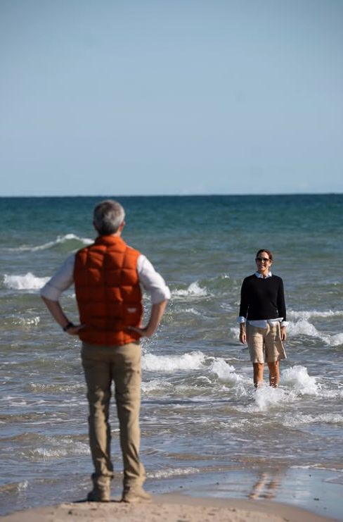 King Frederik of Denmark watches as Queen Mary paddles in the sea on a day out during a major royal tour