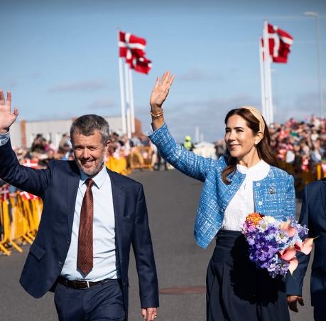 King Frederik and Queen Mary arrive on a tour with Danish flags behind them