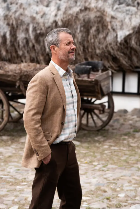 King Frederik walks past a house with a seaweed roof
