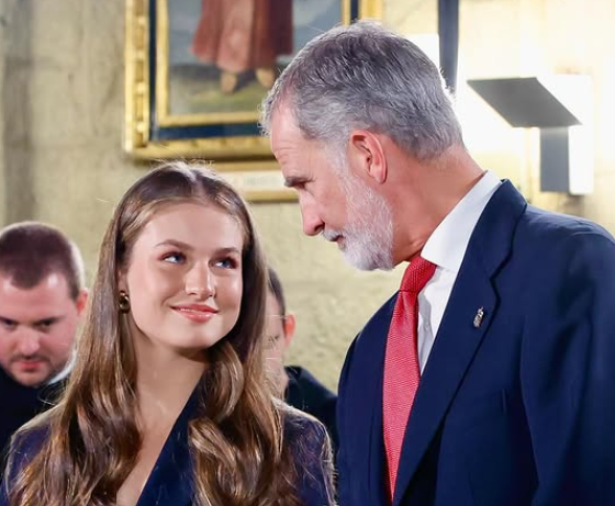 Princess Leonor, in a navy suit, smiles at her father, King Felipe VI of Spain