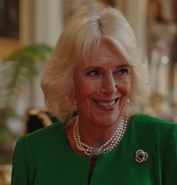 Queen Camilla wears a green dress with a pearl choker necklace and diamond brooch as she inspects a State Banquet at Windsor Castle