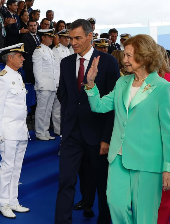 Queen Sofia of Spain wears a green trouser suit and waves at a crowd