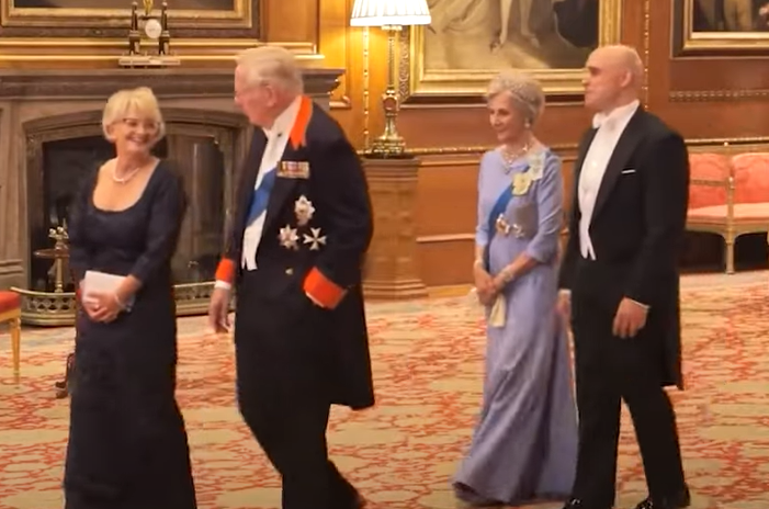 The Duchess of Gloucester walks into the State Banquet at Windsor wearing a pale blue dress and the Honeysuckle tiara