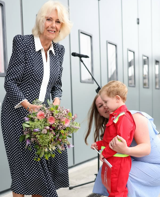 Queen Camilla is given flowers during a visit to name a helicopter in Cornwall