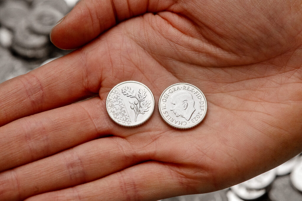 The first 5p coin with King Charles III on it shown next to the oak leaf design on its other side
