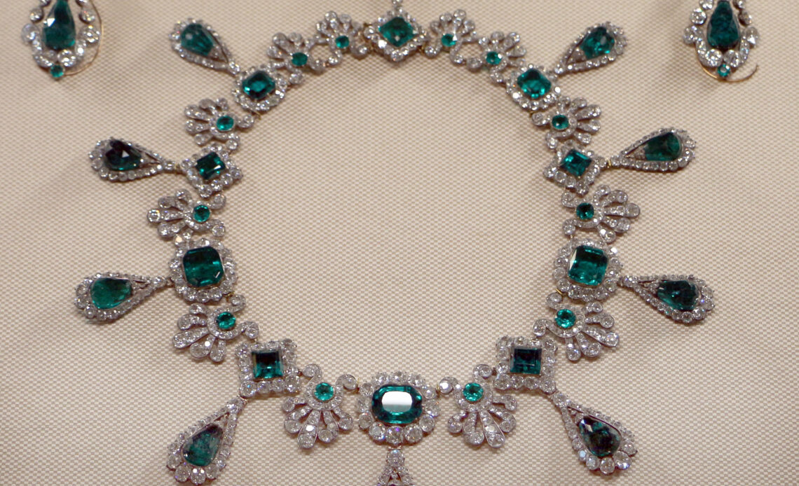 Emerald and diamond necklace laid out on a white table in Paris