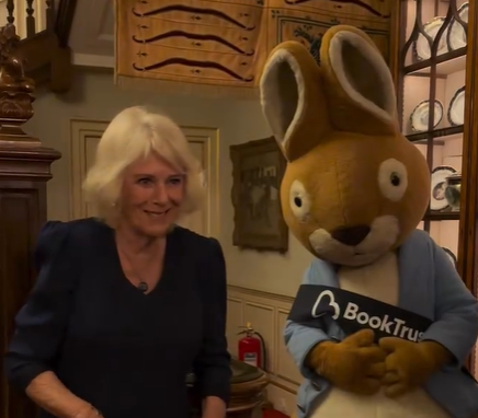Queen Camilla wears a blue dress to meet Peter Rabbit who is wearing his famous blue coat