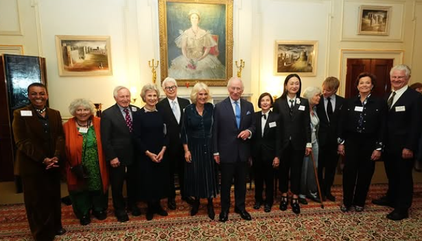 Queen Camilla stands at the centre of a large group of writers including Dame Jilly Cooper
