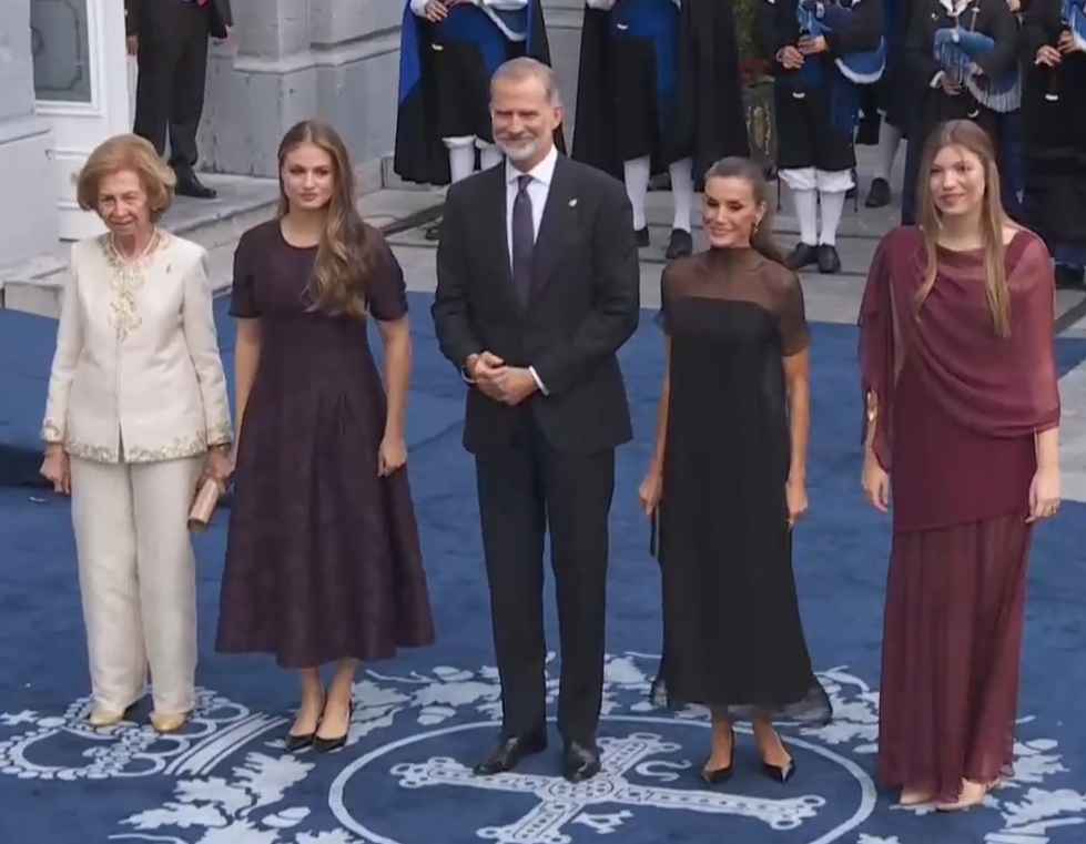 King Felipe and Queen Letizia stand on a blue carpet with a crest on it