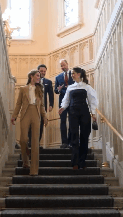 The Princess of Wales, wearing a tan suit, walks down stairs inside Windsor Castle with Princess Rajwa of Jordan