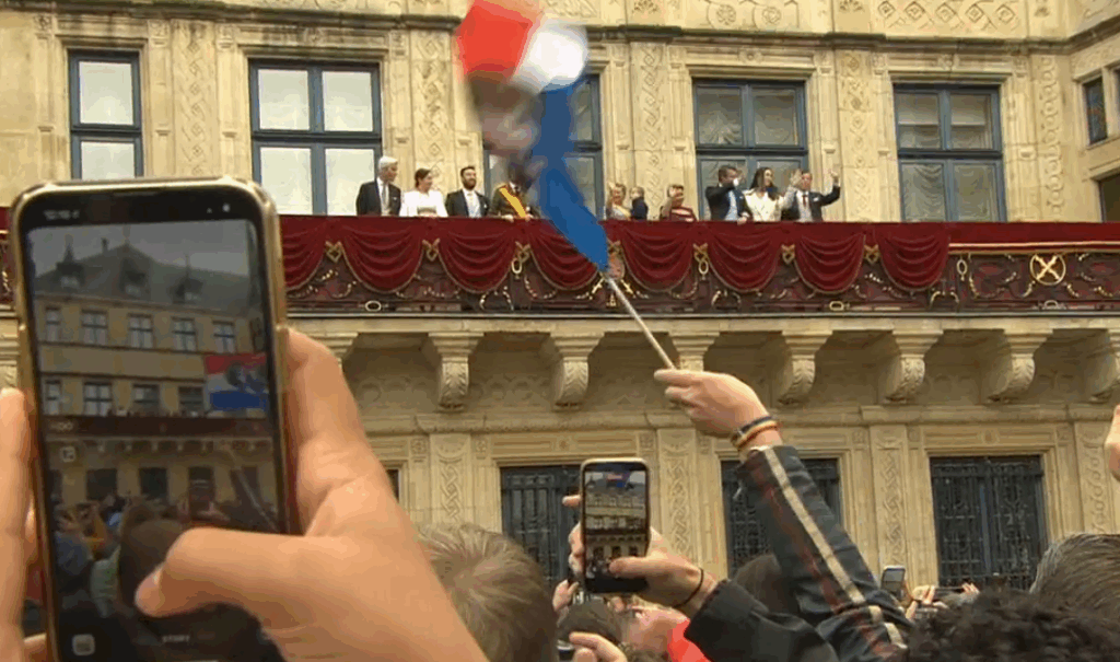 A person in the crowd takes a photo on their mobile phone of Luxembourg's royal family