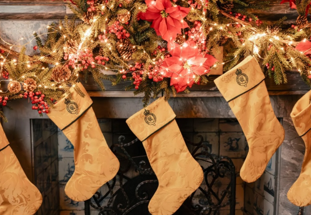 Golden Christmas stockings hang on a festive fireplace decked in red and gold at Dumfries House, one of the homes of King Charles in Scotland