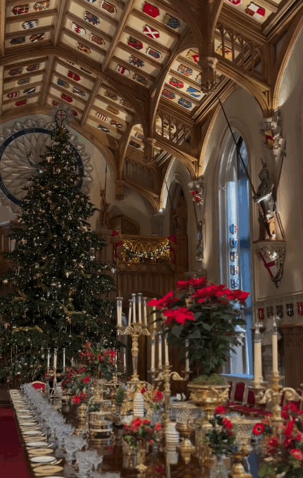 A giant Christmas tree stands in St. George's Hall, Windsor with red flowers beneath it