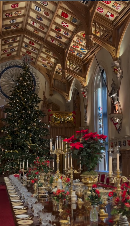 A giant Christmas tree stands in St. George's Hall, Windsor with red flowers beneath it