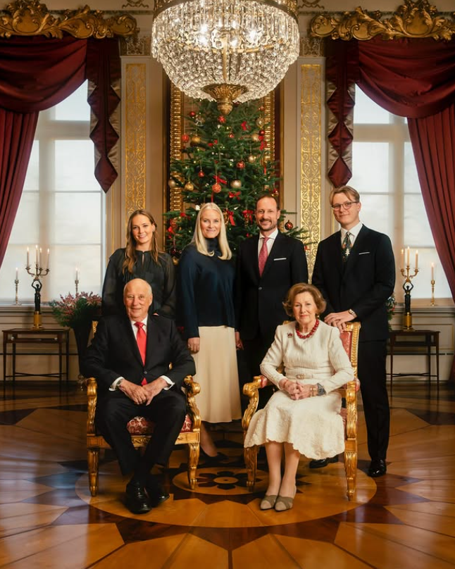The King and Queen of Norway with their family pose in front of a Christmas tree decked in red baubles