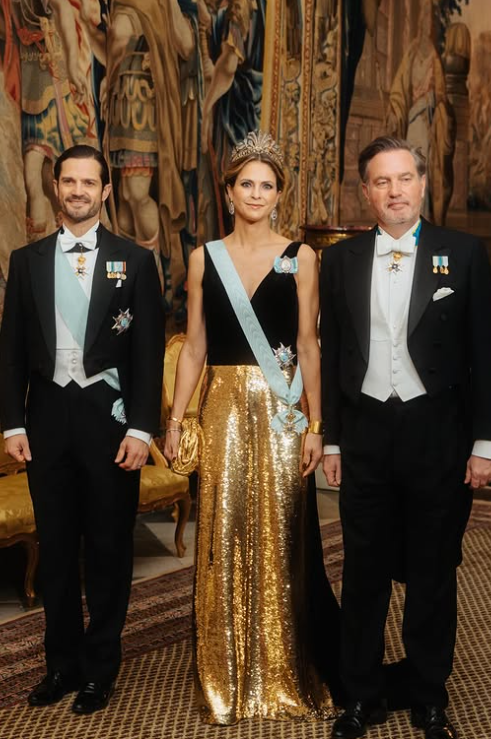 Princess Madeleine in a gold sequinned dress stands next to her brother, Prince Carl Philip, and her husband, Christopher O'Neill
