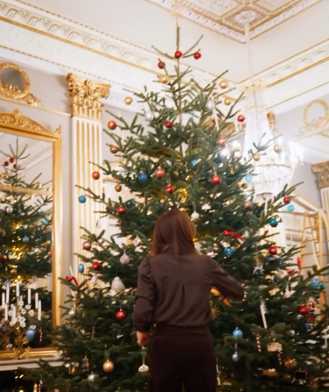 Queen Mary of Denmark hangs Christmas decorations on a tree