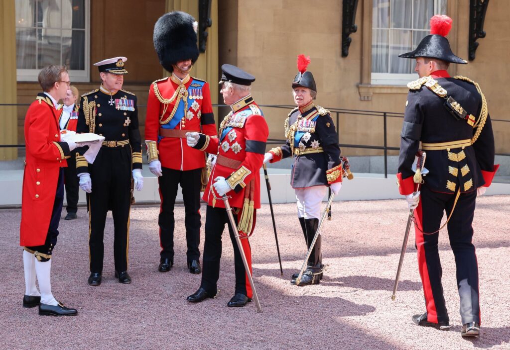 King Charles talks to Prince William while Princess Anne looks on