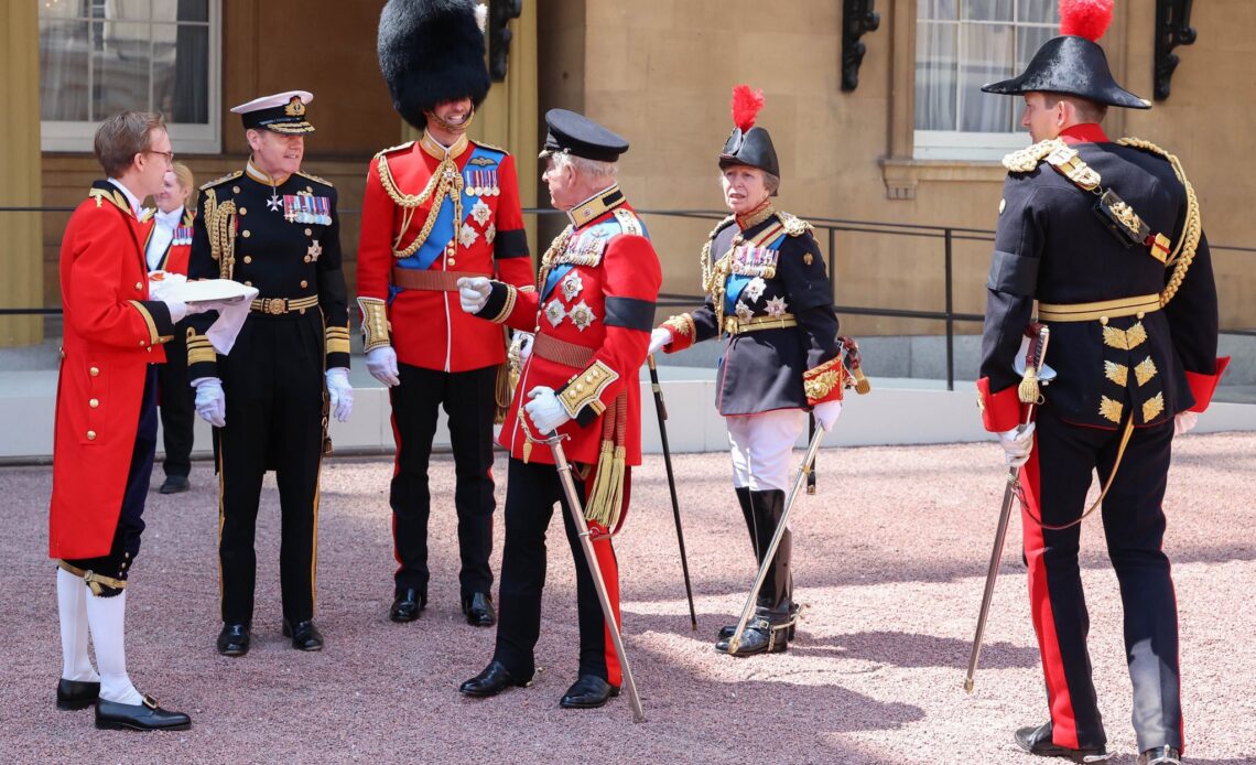 King Charles talks to Prince William while Princess Anne looks on