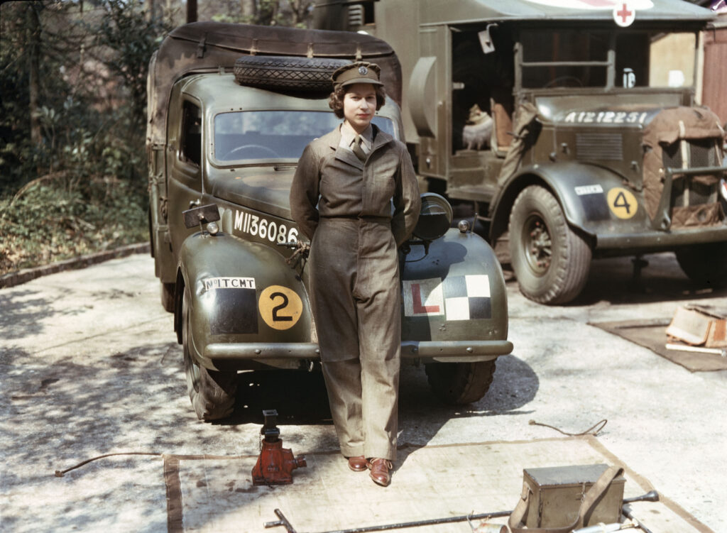 Queen Elizabeth II stands in front of a car during her WW2 service
