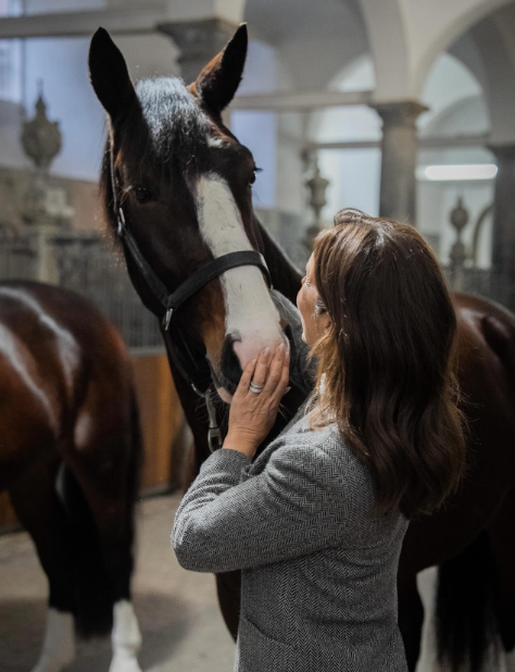 Queen Mary pets a horse at the royal stables in Copenhagen