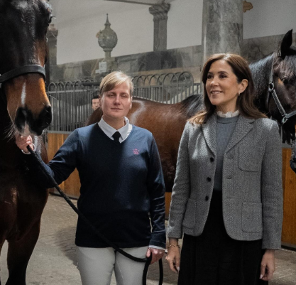 Queen Mary wears a grey jacket and black skirt while she visits the stables in Copenhagen