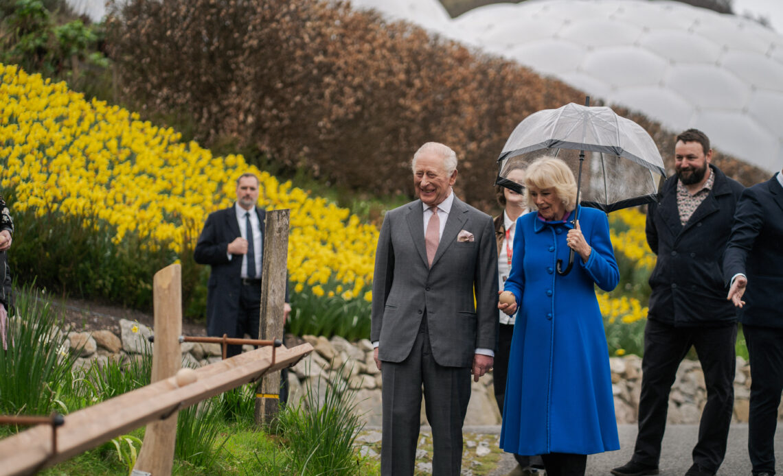 King Charles and Queen Camilla walk through the Eden Project, passing a bank of yellow flowers