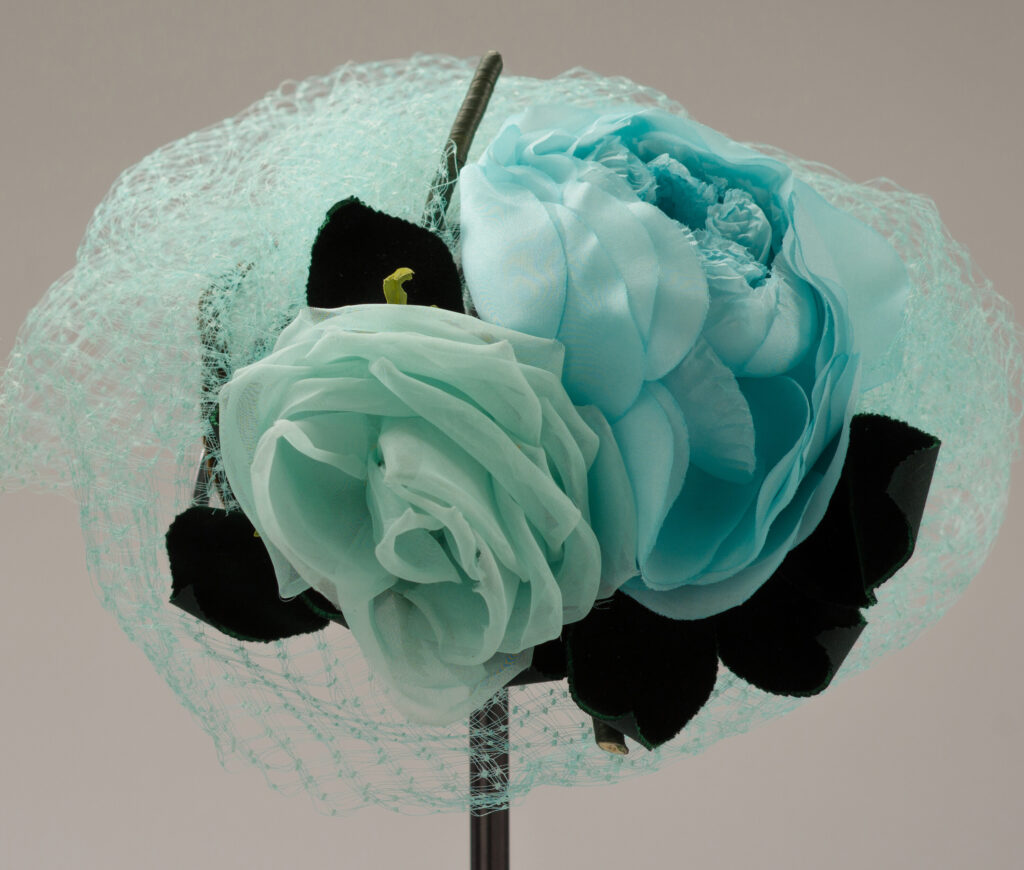 A turquoise fabric flower on a net covered hat