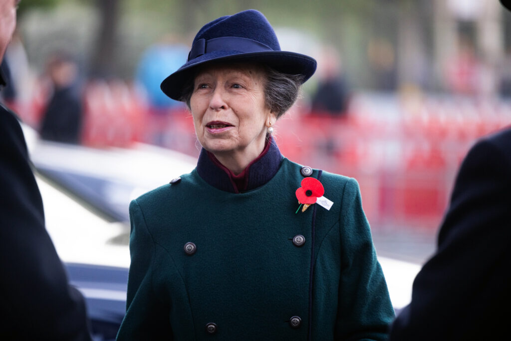 Princess Anne wears a green coat with a red poppy