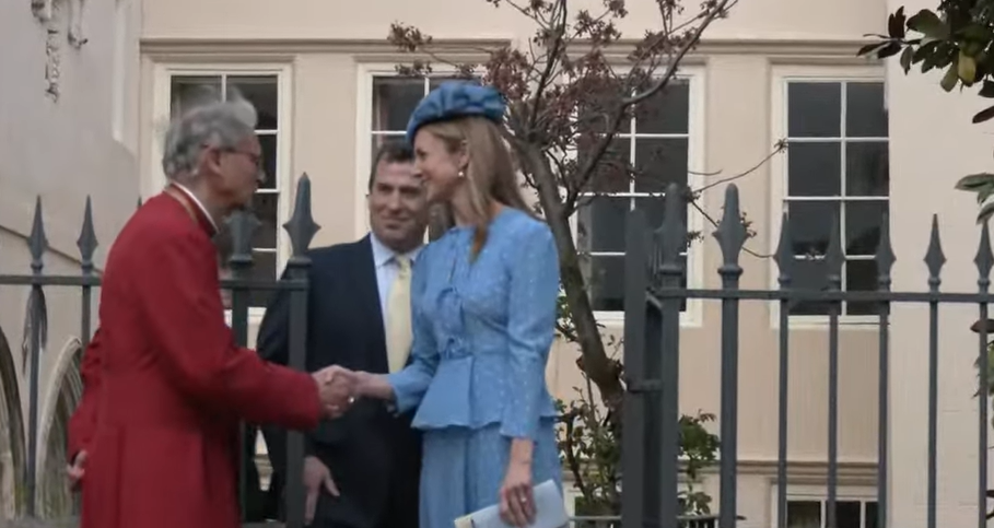 Harriet Sperling in a blue dress, greets a clergyman at WIndsor